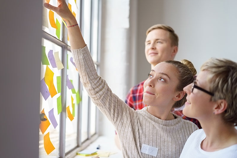 2 Frauen und 1 Mann erarbeiten ein Konzept mit Hilfe von Post-it-Zetteln